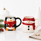 Les deux mugs de Noël côte à côte, pingouin noir et bonhomme de neige crème