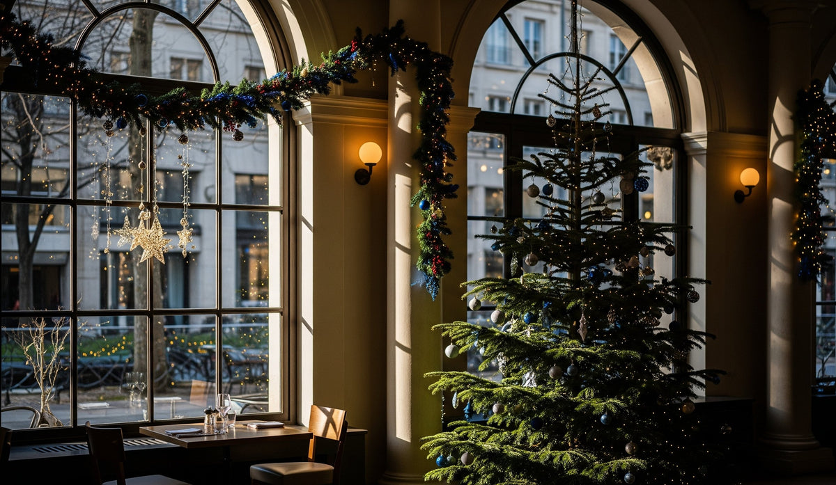 Grote kerstboom in blauw en zilver in een restaurantzaal met hoge boogramen