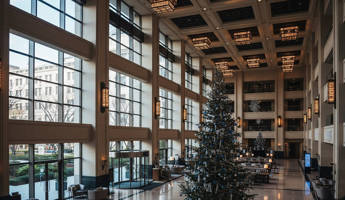 Kerstboom van meerdere meters in een kantoorhal met dubbele hoogte, naast de onthaalbalie